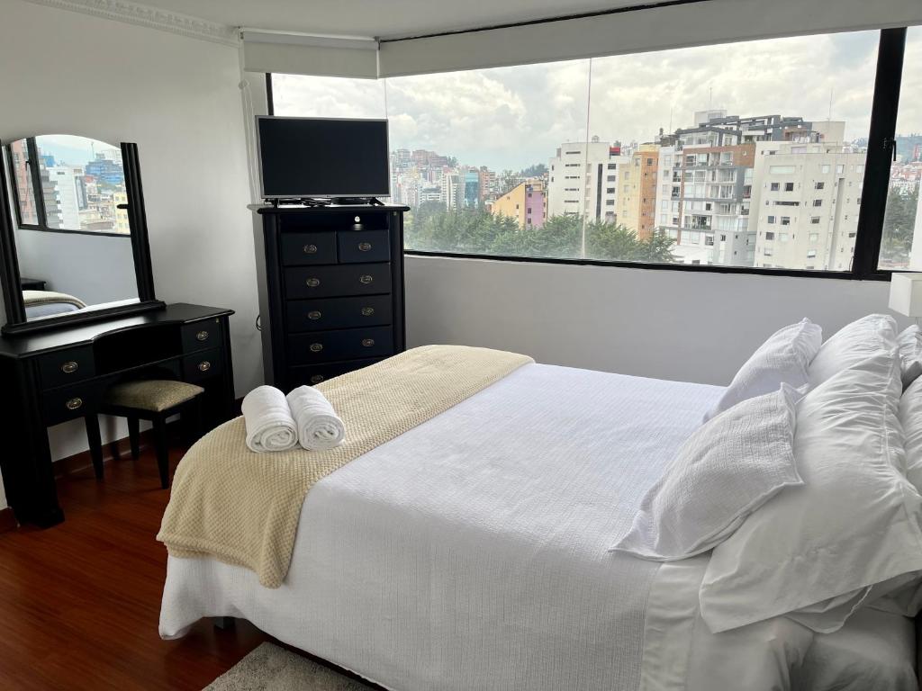 基多Suite amoblada con aparcamiento privado excelente vista y ubicación! Sector La Carolina的一间卧室配有一张床、一张书桌和一个窗户。