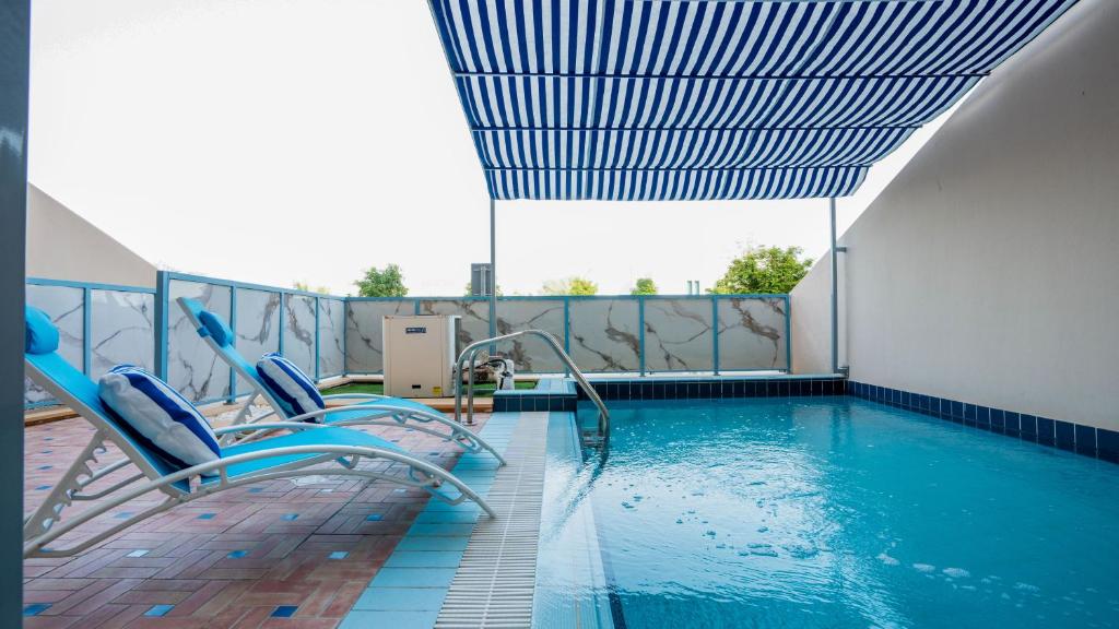 迪拜Exclusive Retreat GLOBALSTAY's New 3BR Townhouse with Private Pool的游泳池旁带两把椅子的游泳池