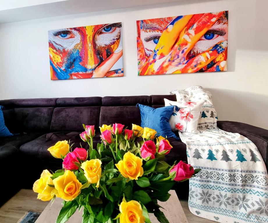 耶莱尼亚古拉Apartament Jelonek w Karkonoszach的客厅配有带鲜花和绘画的沙发