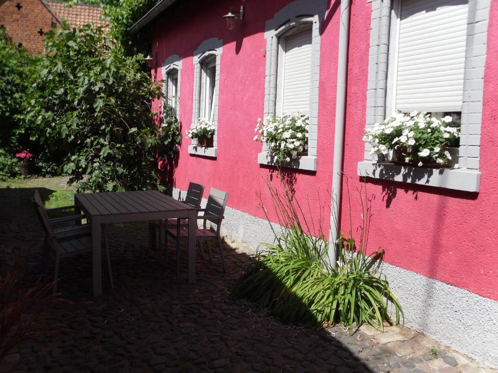 葡萄酒之路上的诺伊施塔特Winzeranwesen - Weingut Christian Eberley - Haupthaus I MINDESTAUFENTHALT 3 NÄCHTE - MINIMUM STAY 3 NIGHTS的粉红色建筑前的桌椅