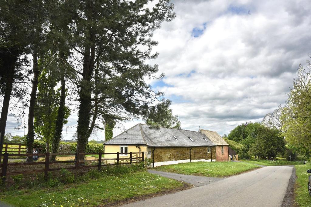 阿宾汉姆The Old Stables at Castle Chase, Ayston的路边有围栏的旧建筑