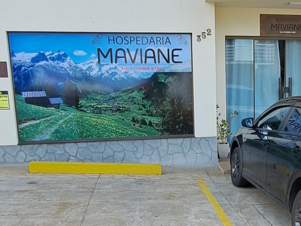 特雷齐蒂利亚斯Hospedaria Maviane Executive的建筑物一侧的标志,前面有停车位