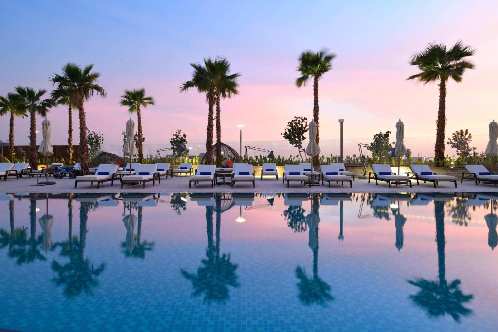阿布扎比InterContinental Residences Abu Dhabi, an IHG Hotel的一个带椅子的游泳池,棕榈树