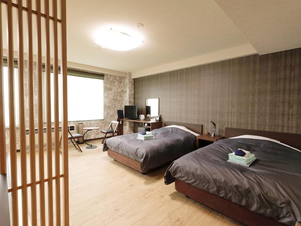 ChikuniApprising hotels GranJam Tsugaike - Vacation STAY 77381v的一间卧室配有两张床和一张带电脑的书桌