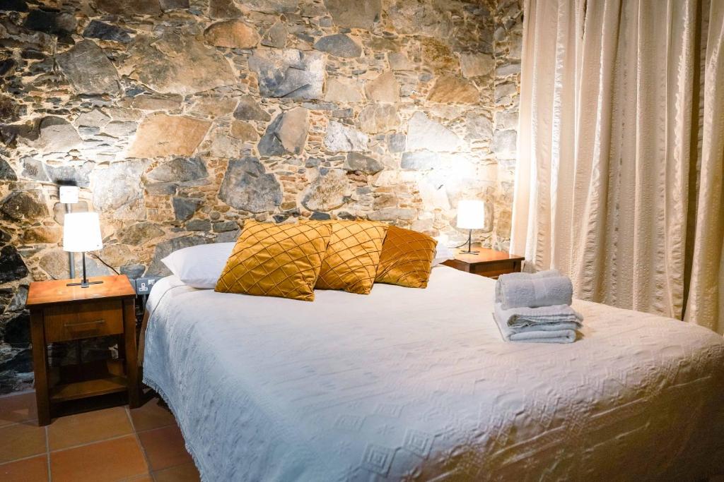 尼科西亚Archontiko Rousias的一间卧室配有一张带两盏灯和石墙的床。