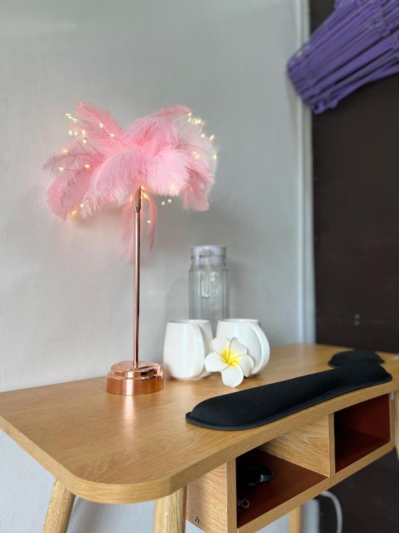 General TriasTaal cozy private homestay with OWN PRIVATE bathroom in General Trias - Pink Room的木桌上的粉红色羽毛灯