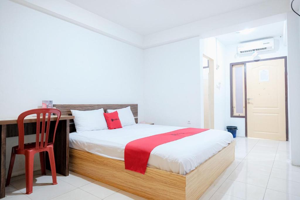 占碑市RedDoorz near Tugu Pers Jambi的一间卧室配有一张床和一张红色椅子
