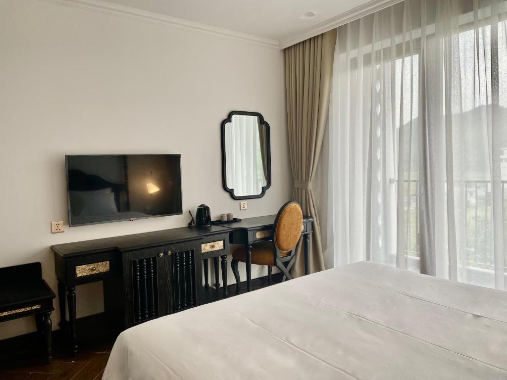 吉婆岛Eden Hotel Cát Bà的一间卧室配有一张床、一张书桌和一台电视