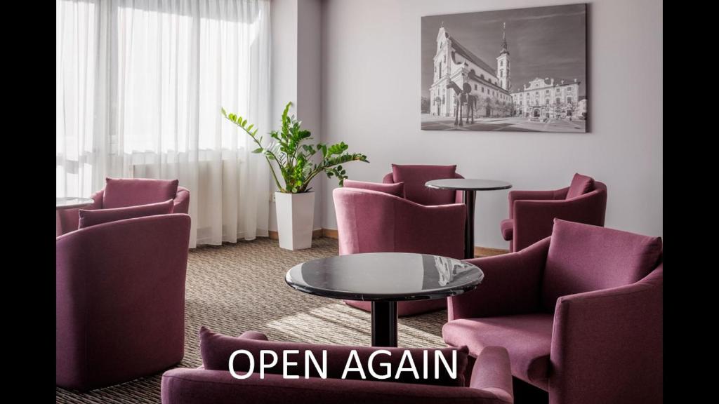 布尔诺OREA Hotel Voro Brno的一间设有紫色椅子和一张桌子的等候室