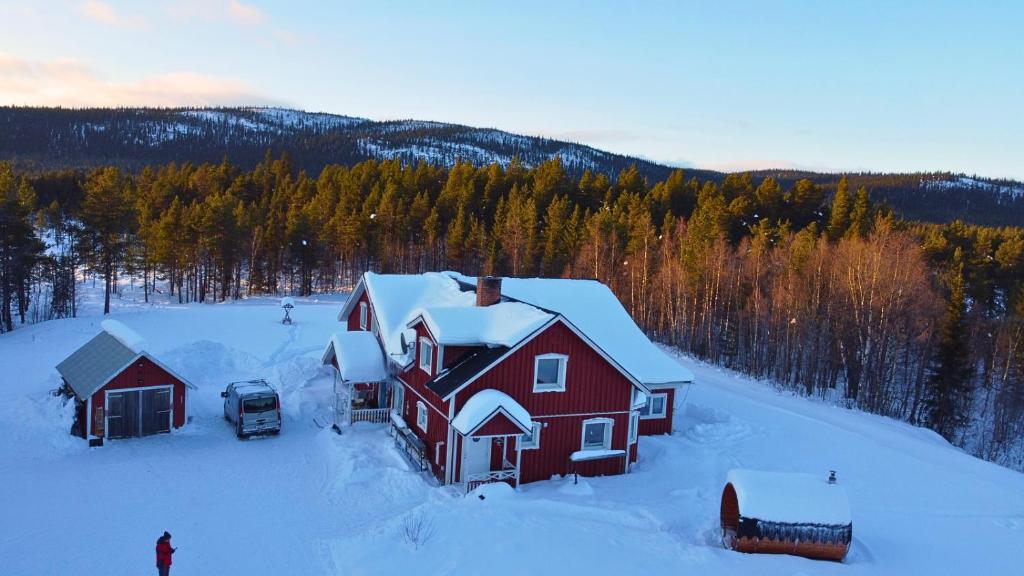 阿尔耶普卢格Villa Björklund的雪中的一个红色房子,旁边停着一辆汽车