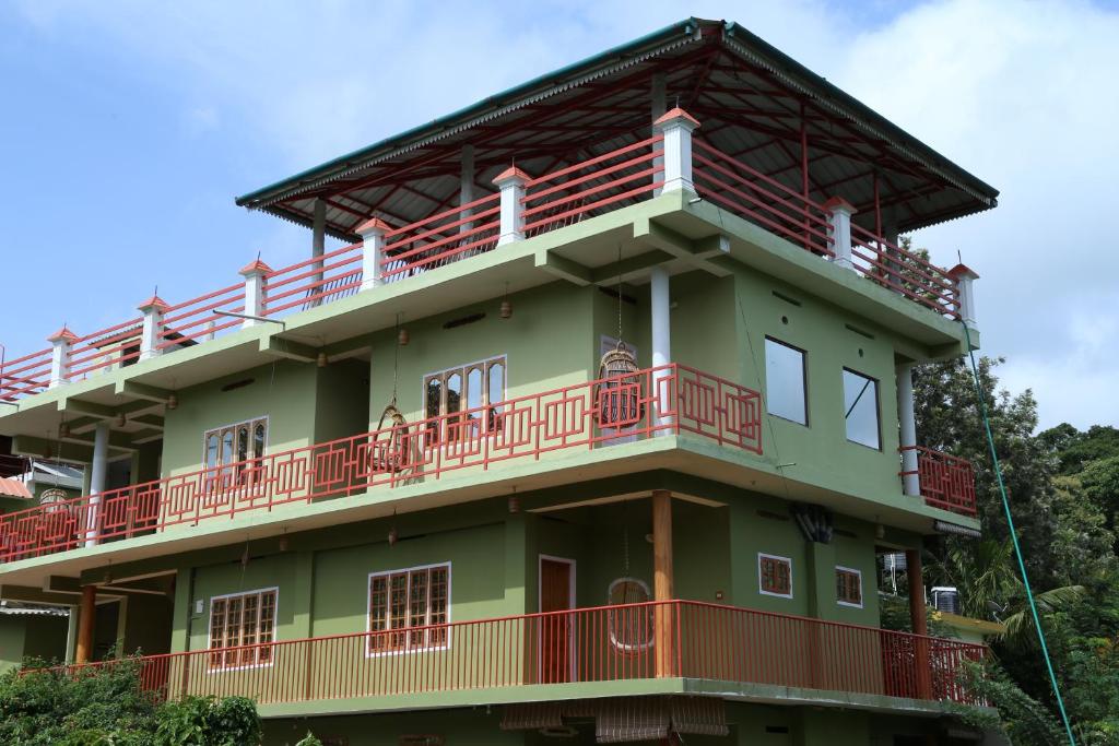 提喀迪Panthalams Homestay的绿色建筑的顶部设有红色阳台