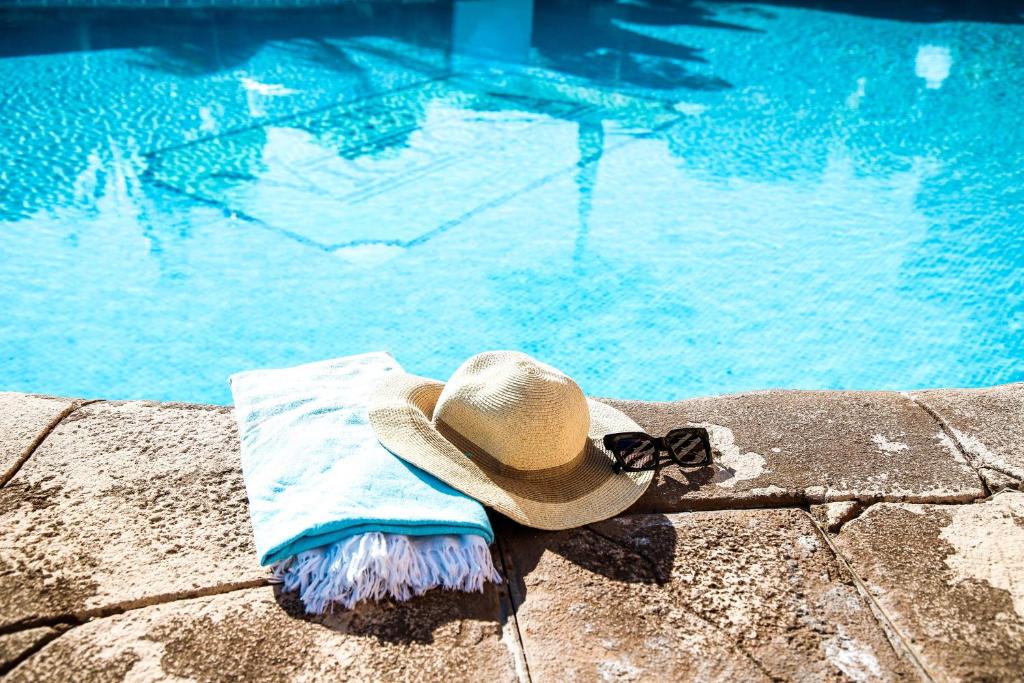 阿尔姆尼卡维多利亚海滩酒店的坐在游泳池旁的草帽