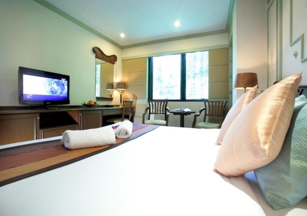 曼谷大华套房酒店的一间卧室配有一张大床和电视