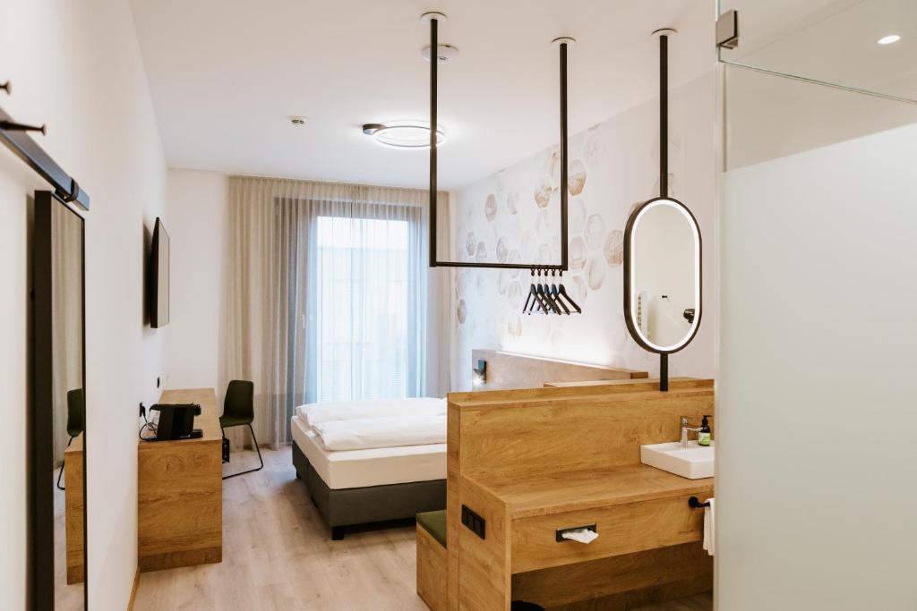 林茨BEE GREEN Linz Self-Check-in-Hotel的一间卧室配有床、水槽和镜子