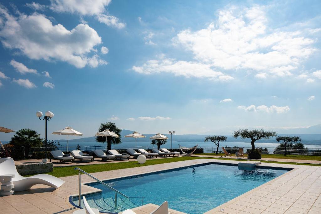 干尼亚Villa Panorama的一个带椅子和遮阳伞的游泳池以及大海