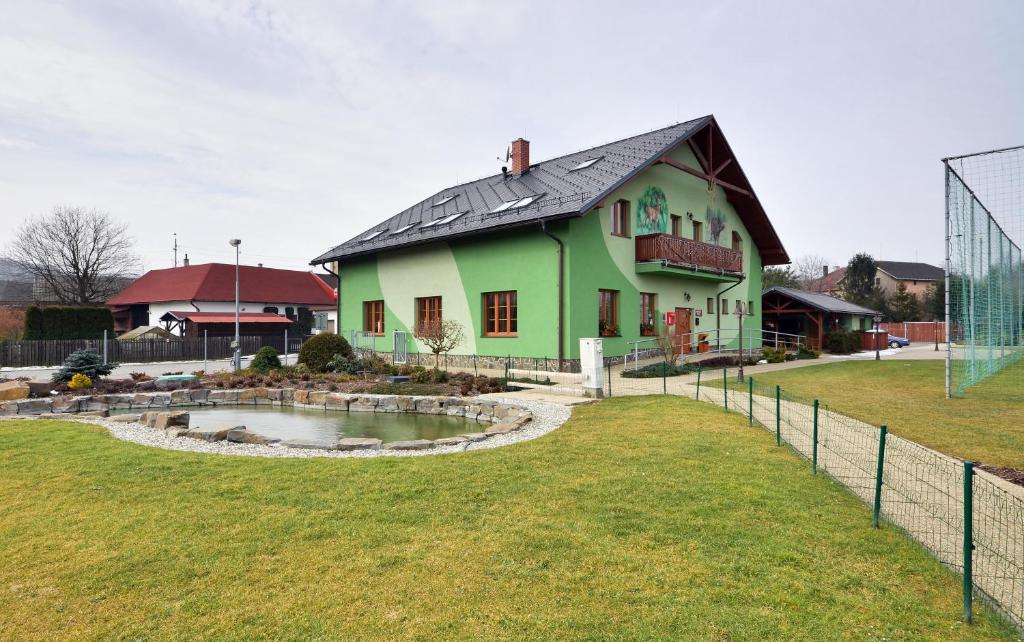 Jilešovice卡蒙内茨膳食公寓酒店及餐厅的田野前带池塘的绿色房子
