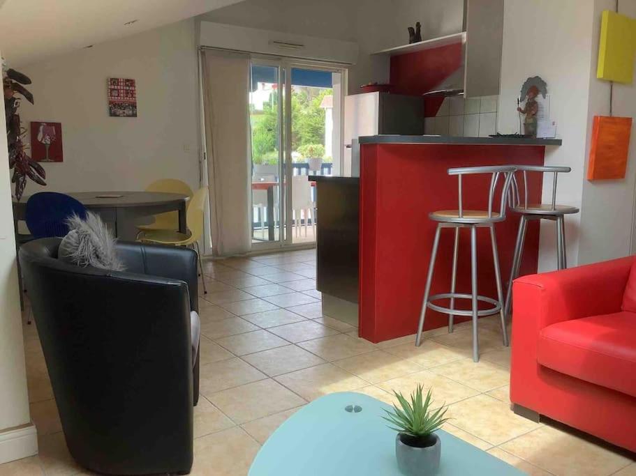 比达尔Bidart côte basque T3 250 mètres de la plage 3***的厨房以及带红色台面的起居室。