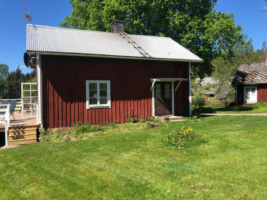 KorsbergaMysig lantlig stuga, Nycklarör的前面有一个草地庭院的红色谷仓