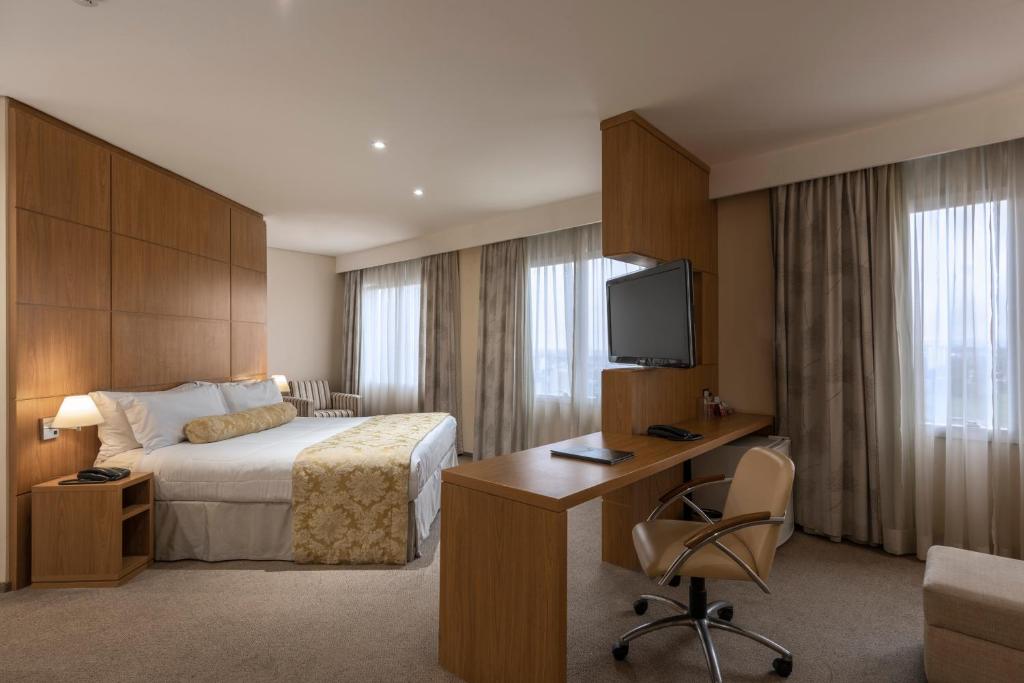 圣若泽杜斯坎普斯Monreale Plus São José dos Campos的酒店客房设有一张床、一张书桌和一台电视机。