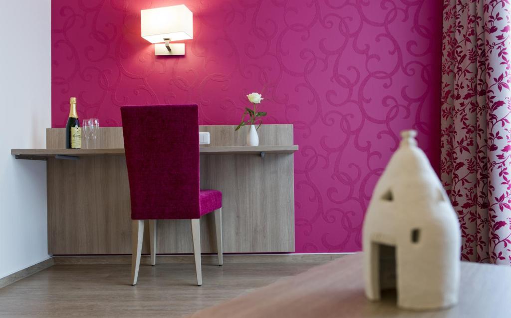 弗隆海姆克劳斯特斯特鲁贝尔酒店的粉红色的房间,配有一张桌子和一张紫色椅子