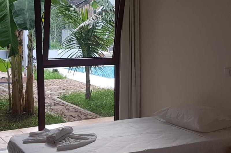 PombasResidencial Lela d'Fermina的一间卧室配有一张床,享有游泳池的景色