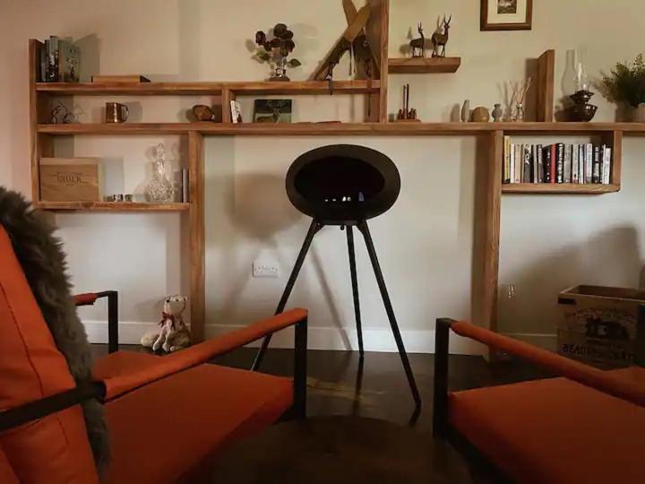 斯特灵The Bothy的客厅配有椅子、桌子和书架