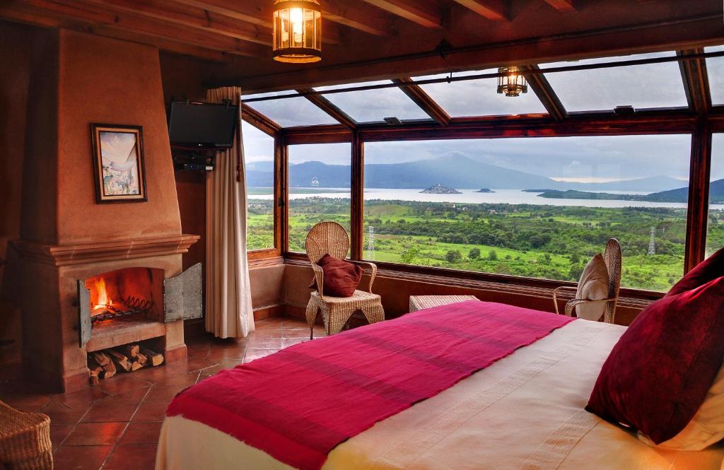 帕茨库卡罗谢洛波登酒店的卧室设有大窗户、一张床和壁炉