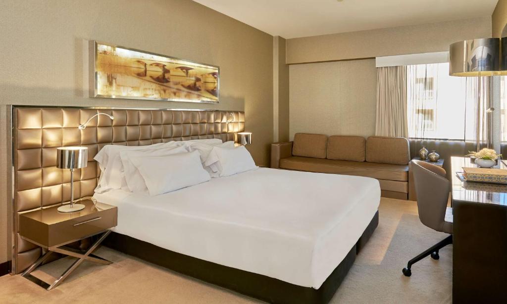 科英布拉NH Coimbra Dona Ines的卧室配有一张白色的大床和一张沙发。