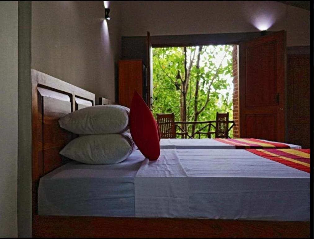 库鲁内格勒THE HIDEOUT KURUNEGALA的一间卧室配有两张带枕头的床和窗户。