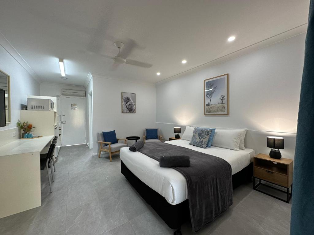 马里巴Mareeba Motor Inn的一间带一张床和一张书桌的卧室和一间厨房