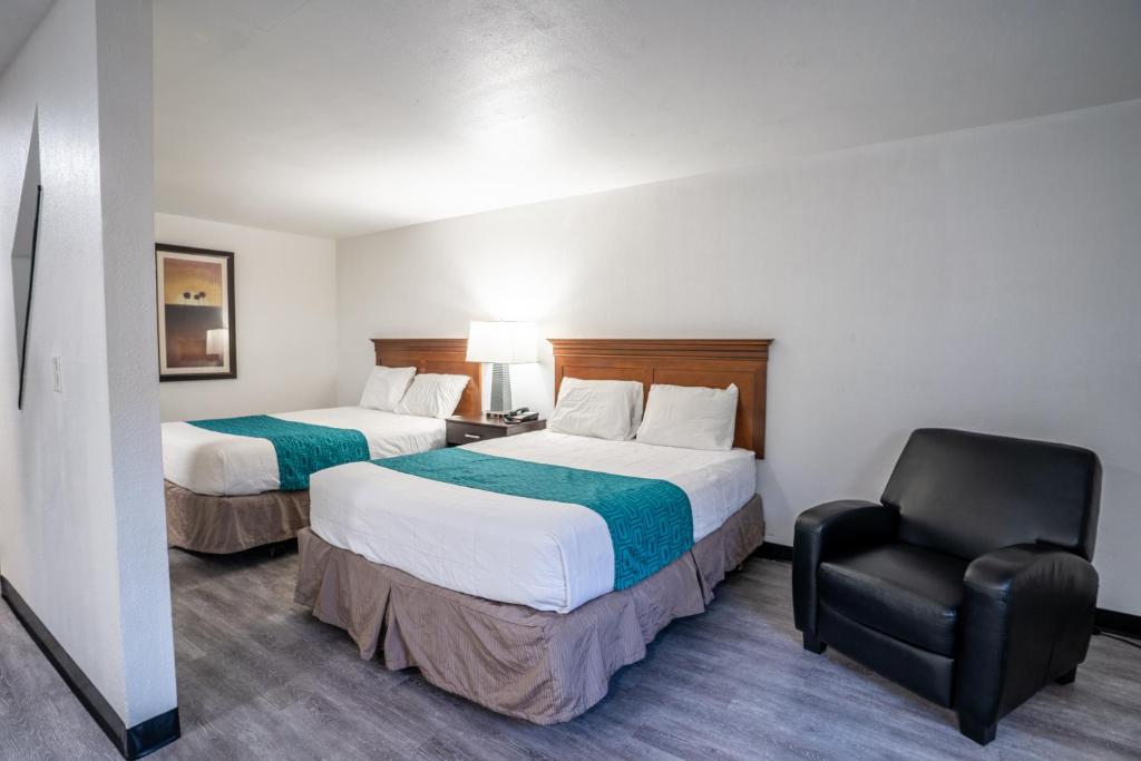 肯纳威克Kennewick Inn & Suites Tri Cities的酒店客房,配有两张床和椅子