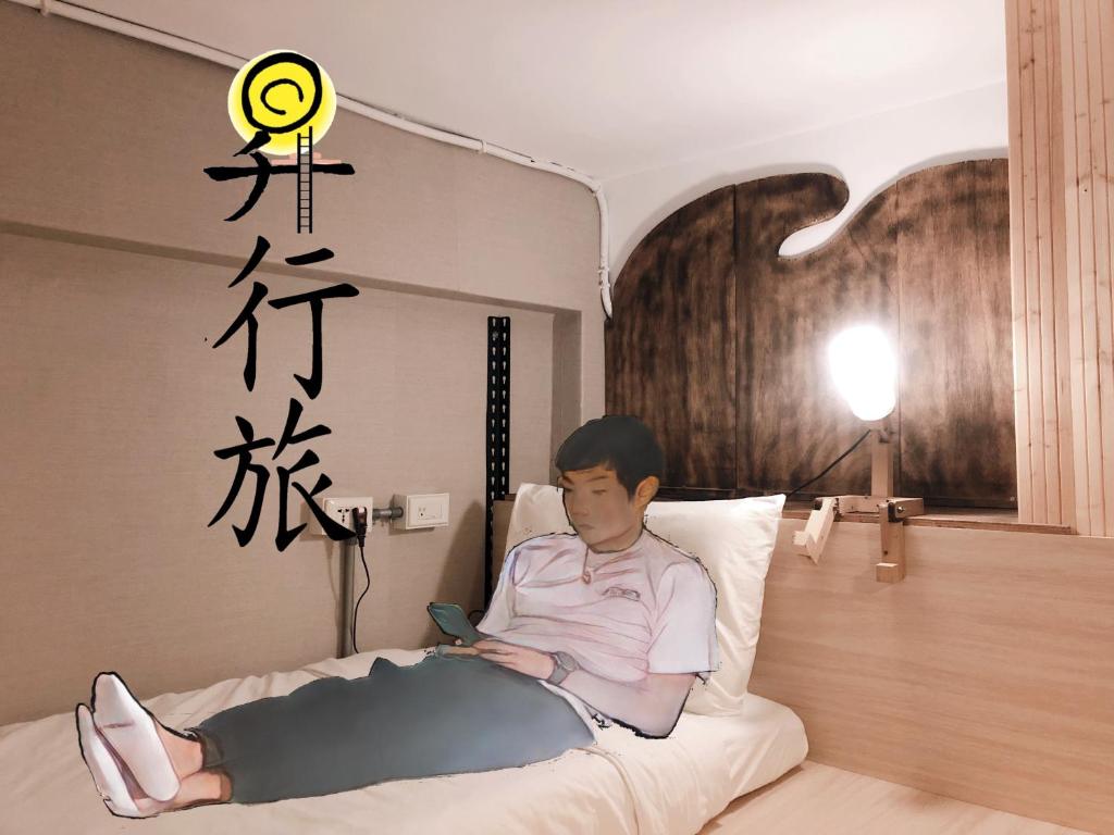 台北Hostel of Rising Sun 昇行旅的躺在床上的男人用手机