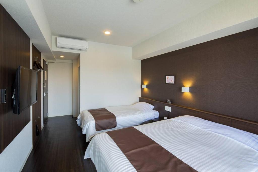 福冈Hotel Grand View Fukuoka-Kuko的酒店客房设有两张床和一台平面电视。
