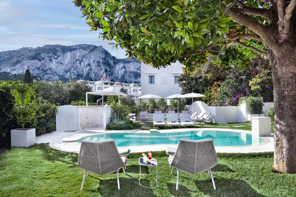 卡普里Pazziella Garden & Suites的一个带游泳池、椅子和房子的花园