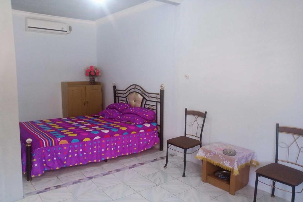占碑市EXPRESS O 92251 Jaya Kusuma Homestay的一间卧室配有一张床、两把椅子和一张桌子