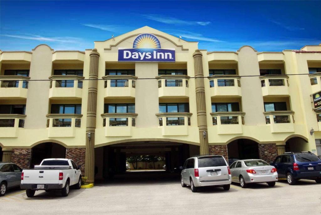 塔穆宁Days Inn Guam - Tamuning的一座大型建筑,前面有汽车停放