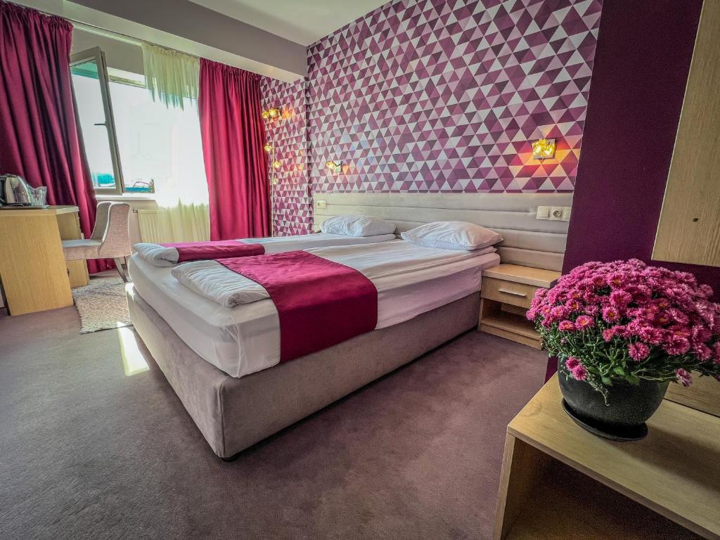 杜普尼察里拉酒店的一间卧室,配有一张床和桌子上的鲜花