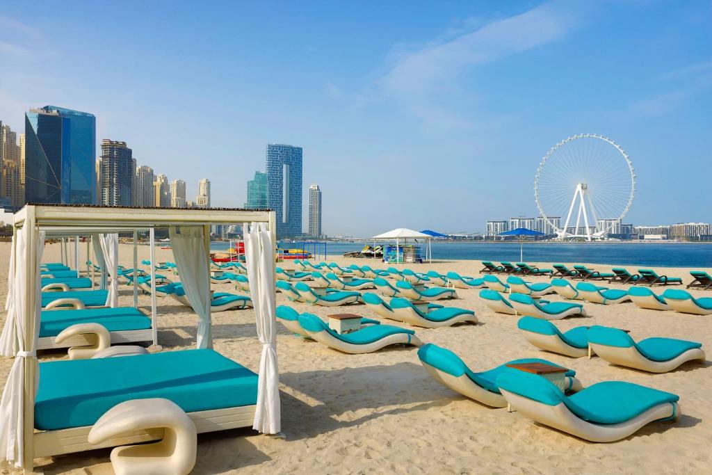迪拜傲途格精选酒店旗下哈布图尔格兰德度假村的一个带躺椅和摩天轮的海滩