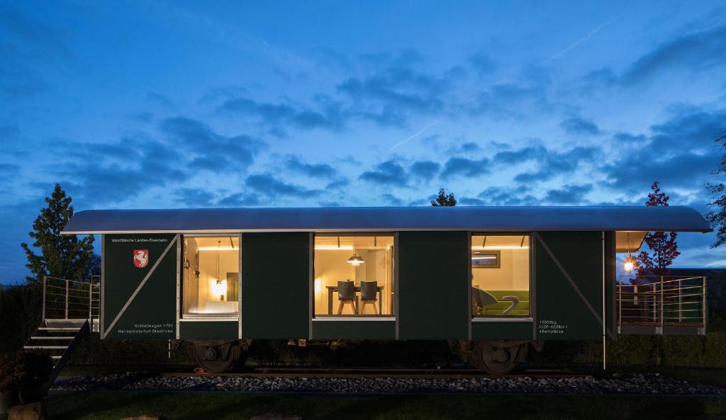 斯塔德特罗恩LokoMotel-Waggon, Luxus Appartment im Eisenbahnwaggon的蓝色屋顶的绿色小房子