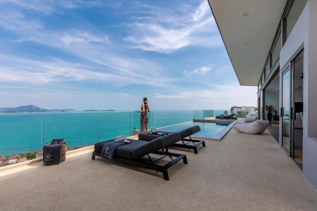 苏梅岛Villa Anushka - Modern luxury villa with picture-perfect sea views的站在海景阳台上的女人
