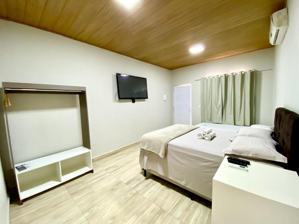 沙帕达-杜斯吉马朗伊斯Pousada Lótus的一间卧室配有一张床和一台平面电视
