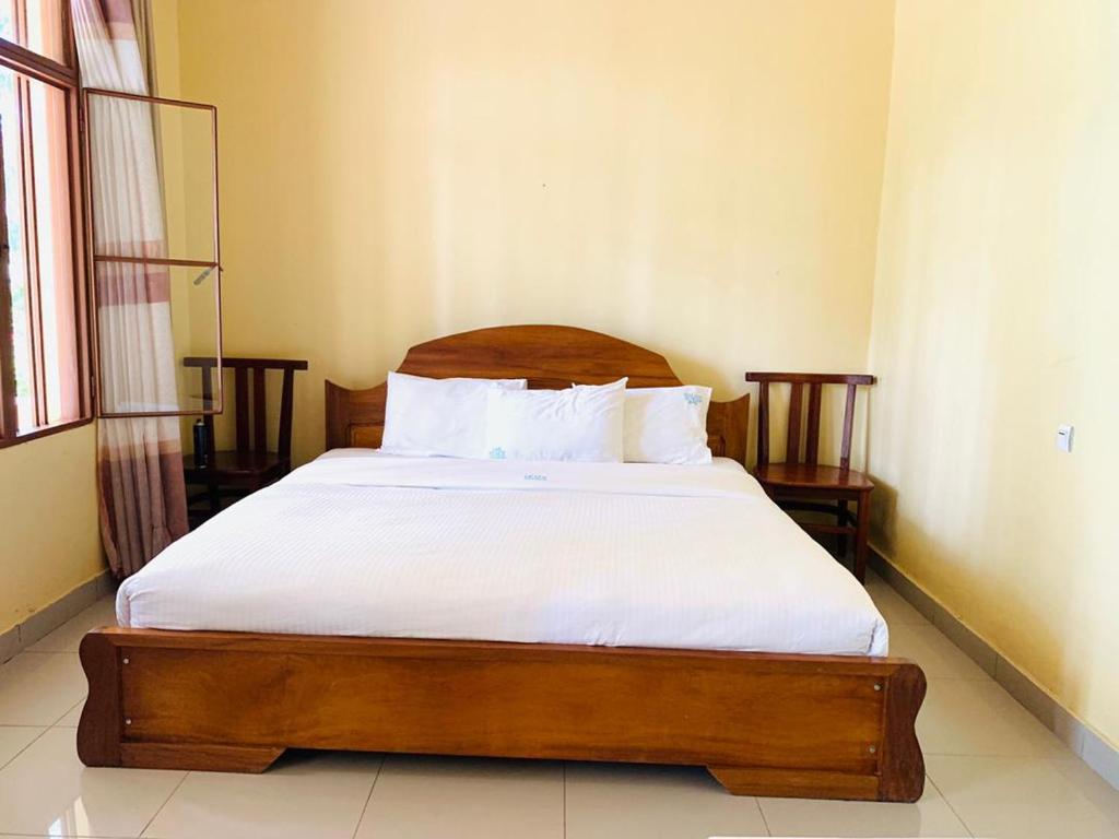 RwumbaEAR KEN BARHAM GUESTHOUSE的一间卧室配有一张带白色床单和枕头的木制床。