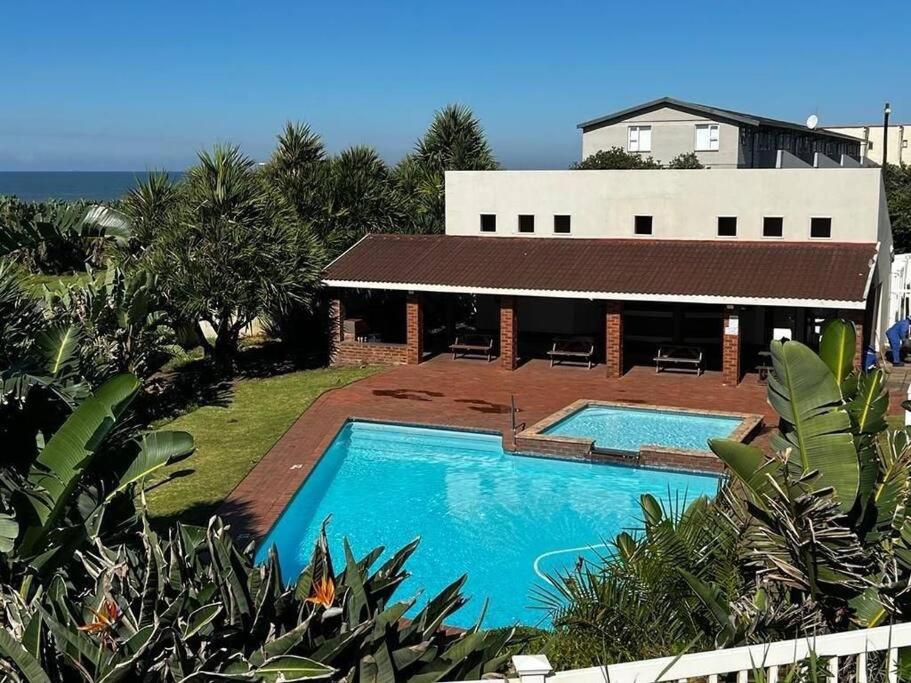 乌旺戈海滩Seaview Beachfront Holiday Apartment - 164 Laguna La Crete的房屋前的游泳池