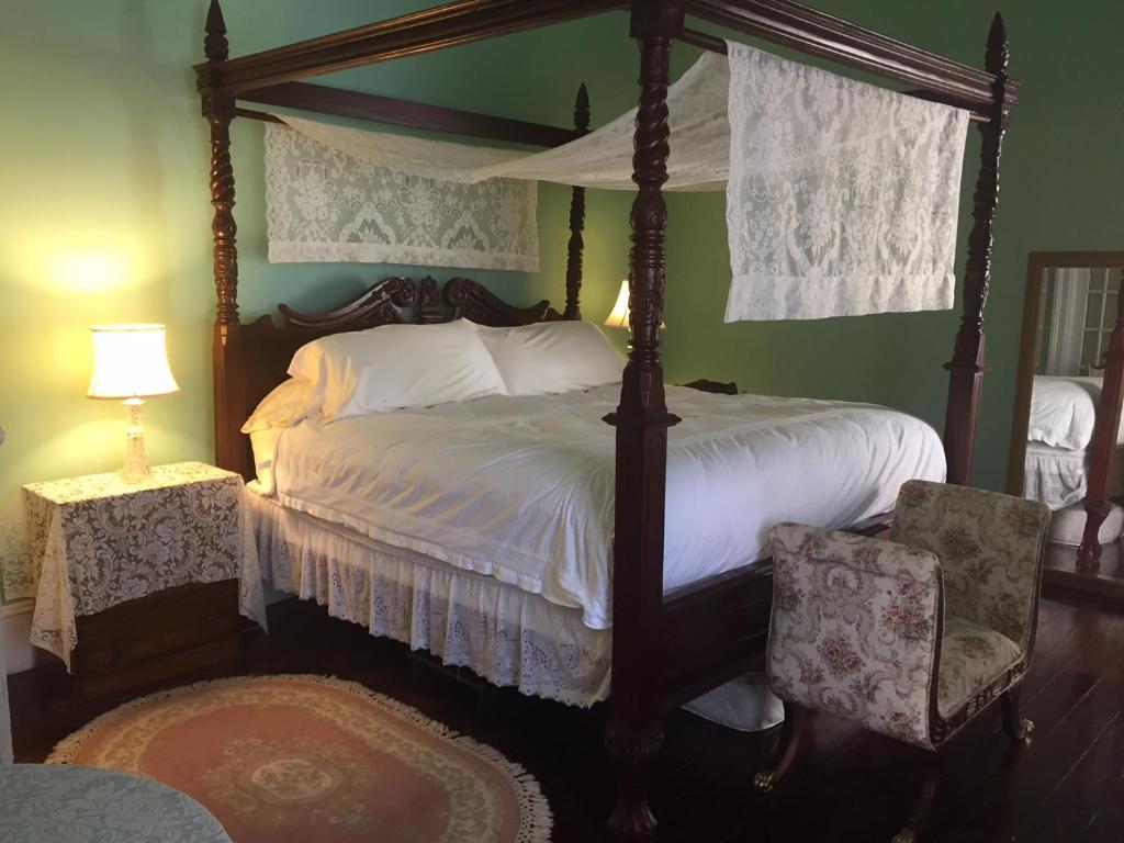 蒙蒂塞洛1872 Denham Inn的一间卧室配有四柱床和两把椅子