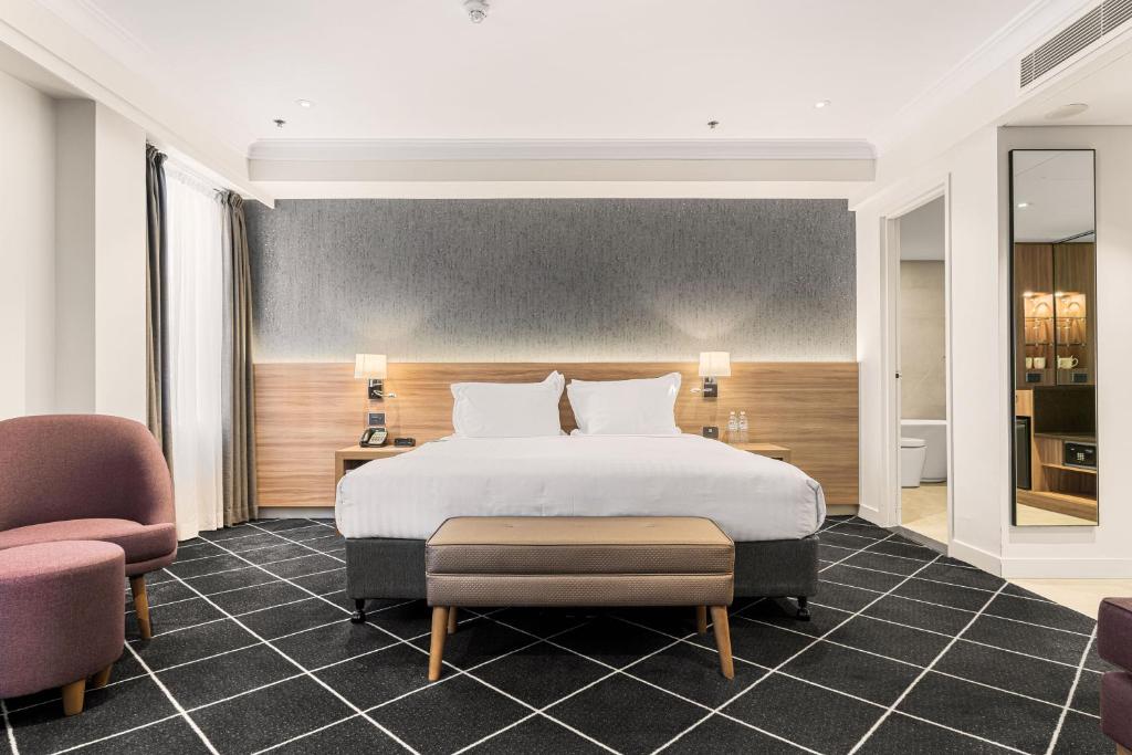 悉尼Furama Darling Harbour的一间卧室配有一张大床和两把椅子
