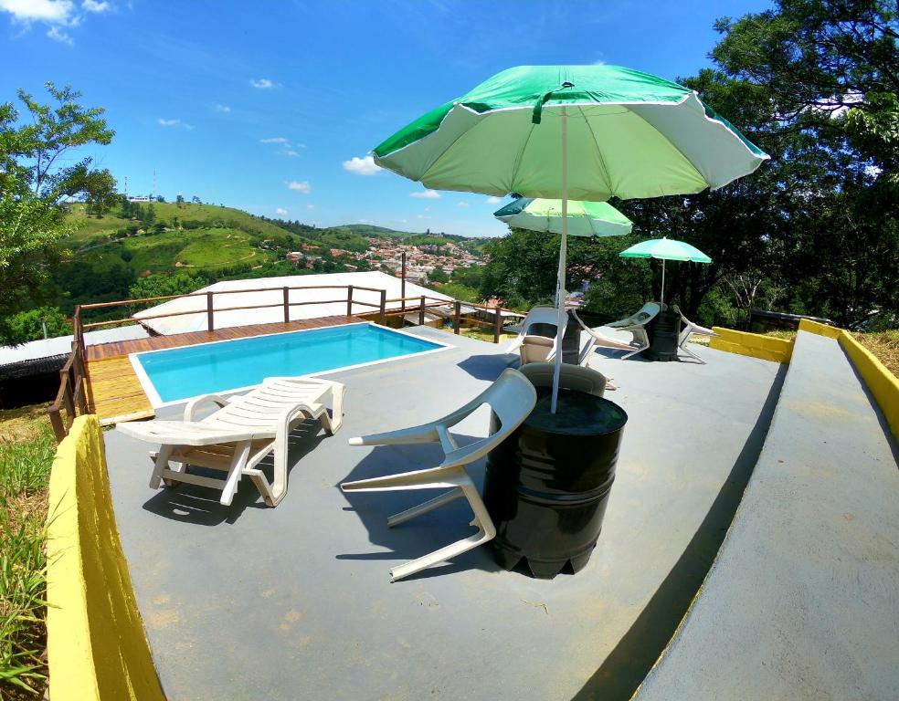 PedreiraPousada Solar da Montanha的一个带绿色遮阳伞和椅子及桌子的游泳池