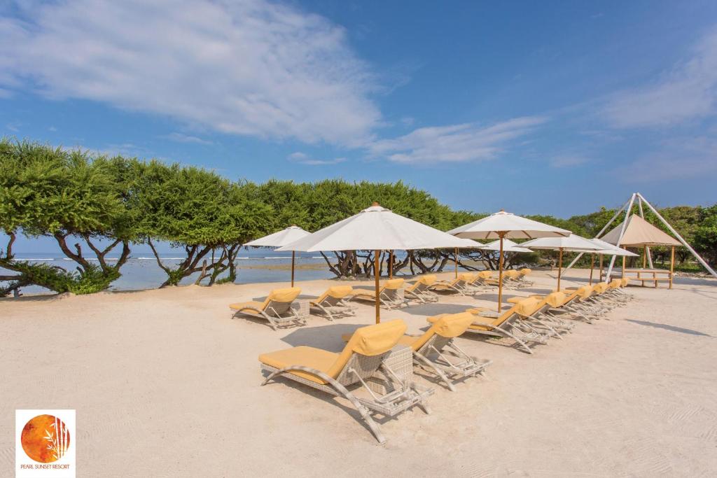 吉利特拉旺安Pearl Sunset Resort的海滩上的一组椅子和遮阳伞