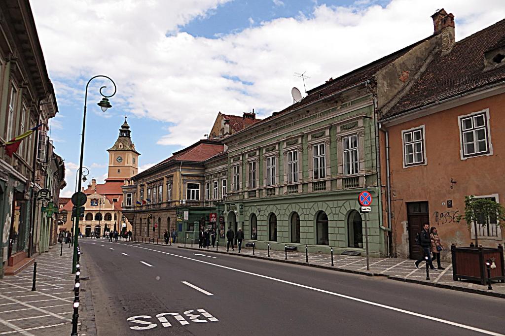 布拉索夫Celebrity Apartment Brasov的一条空荡荡荡的城市街道,有建筑和钟楼
