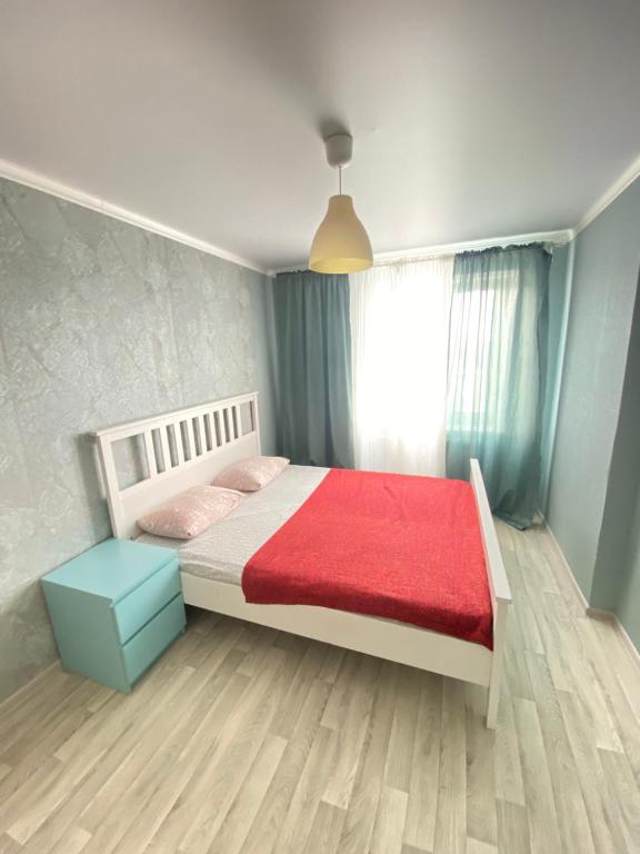阿克托比2-х комнатная квартира напротив аквапарка的一间卧室配有一张带红色毯子的床和窗户。