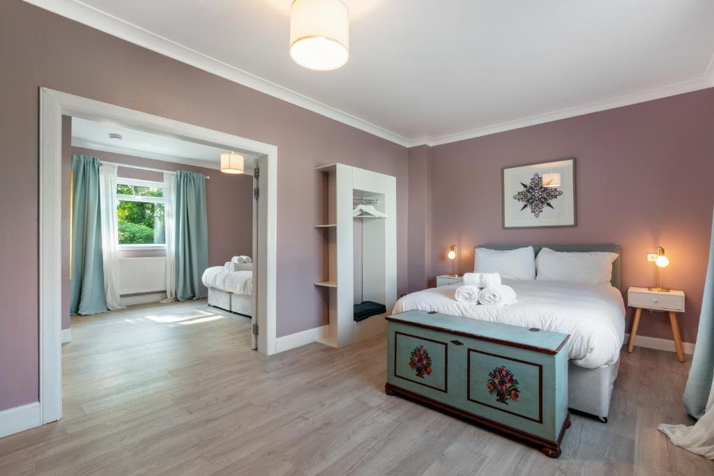 LochwinnochStylish 2 bedroom Cottage near Glasgow Airport的一间带白色床的卧室和一间带粉红色墙壁的房间